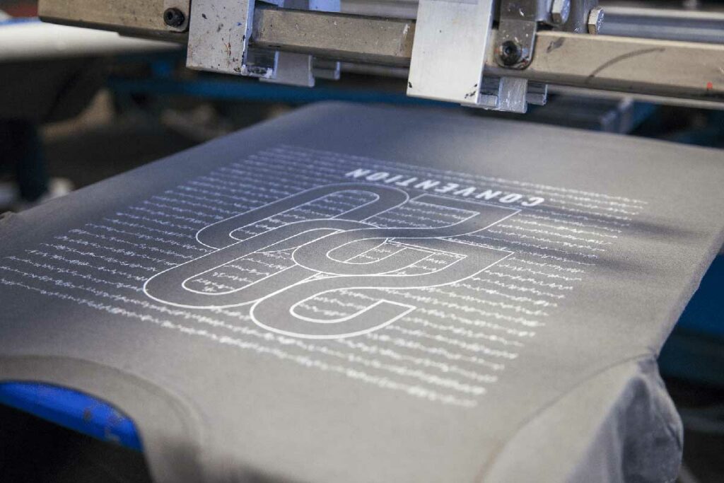grey t-shirt on a screen printer with white text on it